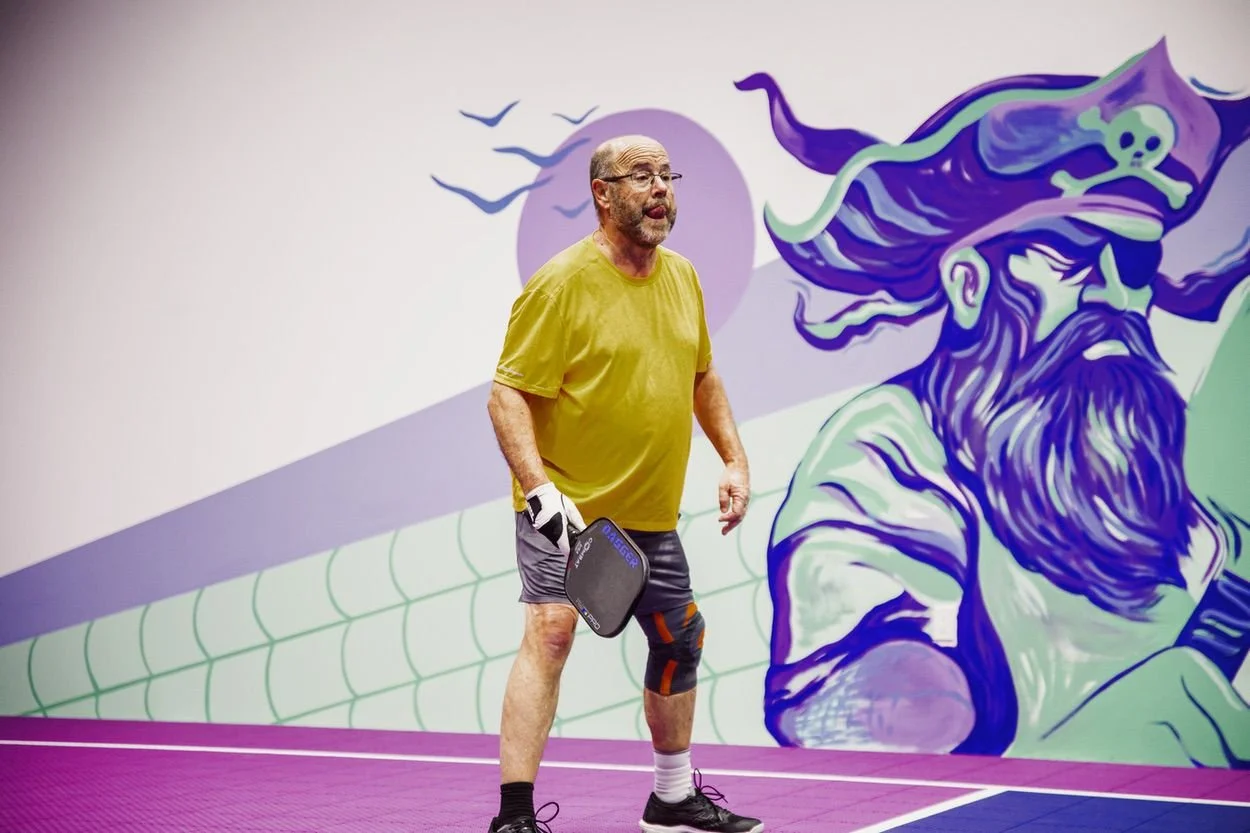 A player in front of the pirate wizard mural inside Pickleball Cove